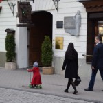 Maza Viļņas meitenīte skaistā sarkanā mētelī brauc ar skrejriteni!