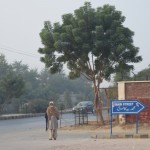 Ir agrs, gaisā vēl rīta dūmaka, un gaisa temperatūra diezgan zema. Vismaz priekš vietējiem noteikti - paskaties, kā vīriņš satinies daudzās šallēs! Mēs, ziemeļnieki, gan bez bēdu tusējam īsajās piedurknēs. Zīme rāda uz Main Street, bet angliskais uzraksts itin nemaz nav paredzēts tūristiem, kā tas sākumā varētu likties (Pakistānā parasti neierodas pārāk daudz tūristu, bet šajā pilsētā jau pavisam noteikti nē), angliski uzraksti ir visur, viscaur valstij - ielu nosaukumi, iestāžu sniegtie pakalpojumi, darba laiki, viss, viss ir ne tikai valsts oficiālajā urdu valodā, bet arī angliski. Droši vien vēl tāda inerce no britu laikiem, hehe.