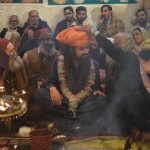 Arī savu milzu turbānu uzvelk manā galvā. Tā esot VISlielākā cieņas izrādīšana. Turbāns gan atšķirībā no krellītēm man pēc tam, protams, bija jāatdod atpakaļ. Visi apkārtsēdošie (un arī desmiti ļaužu, kas sanākuši izrādi skatīties) priecājas par izrādi. Dažu tālāk sēdošo sejās gan var manīt arī apmēram skaudību. Viņi tik centīgi jau ilgu laiku sēž babas aplītī, bet viņiem tāda cieņa nepienākas! Kāda netaisnība! Nuja, bet es esmu bālģīmis, un man piedevām ir tie muļķīgie mati, skaidrs, ka esmu vissvarīgākais, haha! Starp citu, vēlāk mani arī parasti ļaudis uz ielas (pasākuma teritorijā) apturēja un skūpstīja rokas, un aiztika kājas (pēdas potītes). Tāds, lūk, es svarīgs kungs!