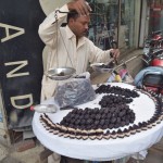 Pēc oficiālo lietu nokārtošanas (darba laika beigām), dodamies pētīt tuvējos bazārus. Vispār man radies priekšstats, ka visa Lahora ir viens vienīgs bazārs - nav tādas vietas, kur nebūtu sastumti tirgotāju galdiņi uz riteņiem, vīri ar maisiem, kastēm u.t.t. Pusdienās izlēmām ēst šos melnumus ar baltām iekšiņām. Pakonsultējāmies ar otru pircēju, kurš, par laimi, prata runāt angliski - šis pastāstīja, cik par šiem jāmaksā, kā tie jāēd u.t.t. Tomēr neprata pastāstīt, kas tas ir. Anglisko nosaukumu nezinot.