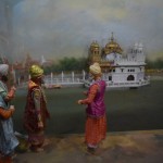 Jau iepriekš stāstīju, kā Randžits veltījis kaudzīti savu iekarojumos un nodokļos ievākto naudiņu Harmandir Sahib tempļa apzeltīšanai, tāpēc, protams, arī tas process šeit ir attēlots - Randžits ieradies pārlūkot darbu procesu. Man patīk, kā te veiksmīgi attēlota perspektīva - tā kā templis ir ļoti tālu (patiesībā pārdesmit centimetru), uz tā jumta strādājošie vīriņi ir kādas desmit reizes mazāki. Labi, bildē izskatās ok, bet īstajā dzīvē bija bišķiņ jocīgi.