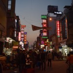 Tā mūsu meinbazārs izskatās vakarā. Kā tāda Las Vegasa, nē? Nez kādēļ izveidojusies tāda situācija, ka tieši šeit iekārtojušās visas lētās viesnīcas, un tieši tāpēc šeit arī ir visvairāk jauno un/vai skopo bālģīmju - arī mēs. Visas viesnīcas ar glaunajām gaismiņu zīmēm gan ir pusklasi augstāk nekā varam atļauties, mūsējā slēpjas šaurā un tumšā sānielā, tieši tādā, kādā pirms šī ceļojuma sākšanas par nekādu naudu nebūtu gājis.