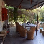 Tā saucamais common room. Cik nu tur room, bet šeit visi no rītiem/pa dienām/vakaros sasēžas ap galdu un runā par visādām svarīgām un nesvarīgām tēmām. Aiz sarkanā lodziņa kreisajā pusē ir virtuve, kurā darbojas Rimdžims - vislēnākais cilvēks pasaulē. Pasūtījumi viņam jāsaka ļoti lēni un jāatkārto vairākas reizes, pēc tam jāgaida kāda pus stunda - stunda (arī, ja esi pasūtījis, piemēram, sviestmaizi vai tēju), un pat tad iespējama situācija, kur pasūtījums ir sajaukts. Visādi citādi Rimdžims ir lāga vīrs no tuvējā ciema, un visu dara pēc labākās sirdsapziņas. Mēs pat viņam beigās atstājām 100 rūpiju dzeramnaudu. Gluži pelnījis nebija, bet tiešām ļoti lādzīgs kungs.